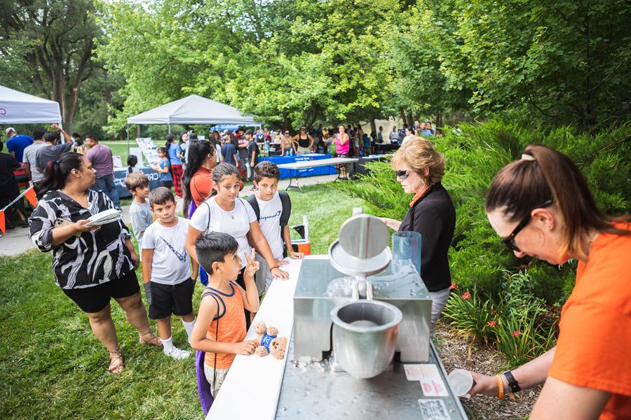 A child excitedly tells Chief Academic Officer Dr. Lorie Cook-Benjamin that he wants not one, but two sno-cones at the booth she and Health & 健康 Director Andreea Baker led during the Back to School 社区 Picnic.