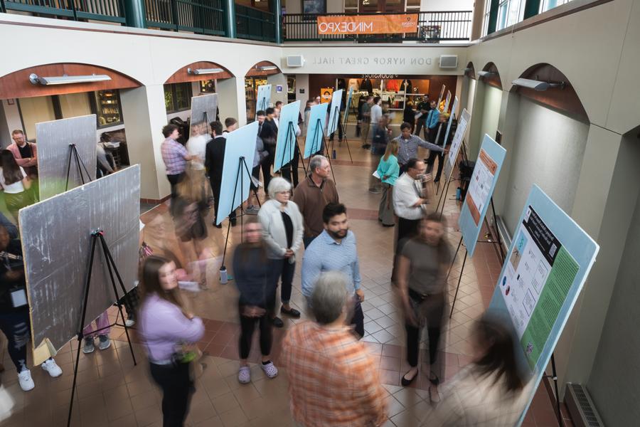 Students, 教职员工和Doane社区成员在展示大三和大四研究项目成果的海报上来回穿梭.