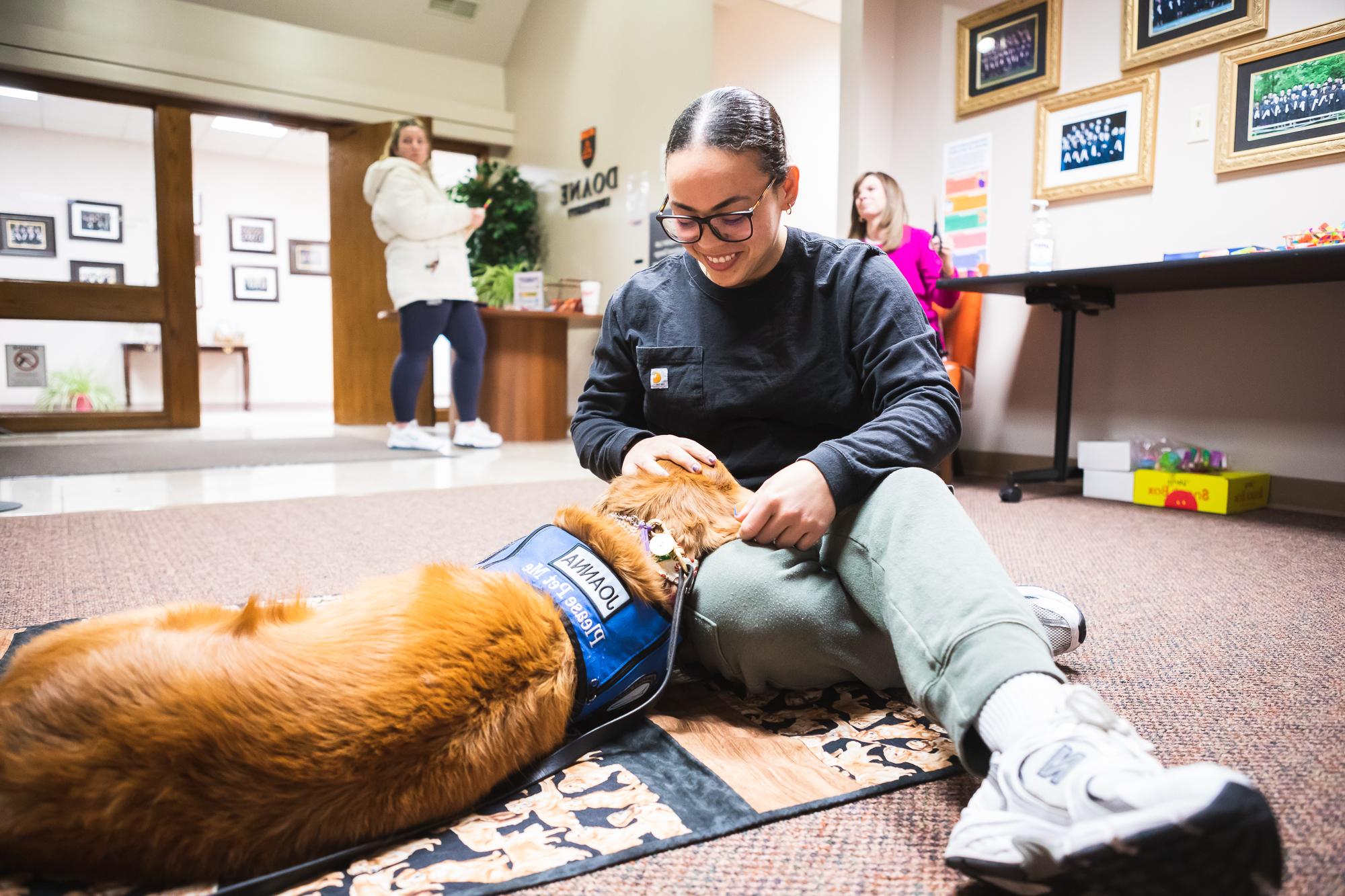 Master of Arts in Counseling student Ekianet Tamayo pets Joanna, a trained therapy dog, during a break between her classes in Lincoln.