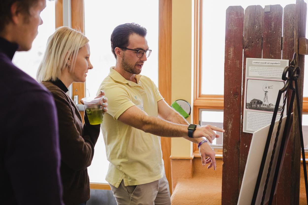 Doane University senior, Travis Handler, gestures to displays showing research he conducted on Black settlers in Nebraska and Native American uses of tallgrass prairie flora. 