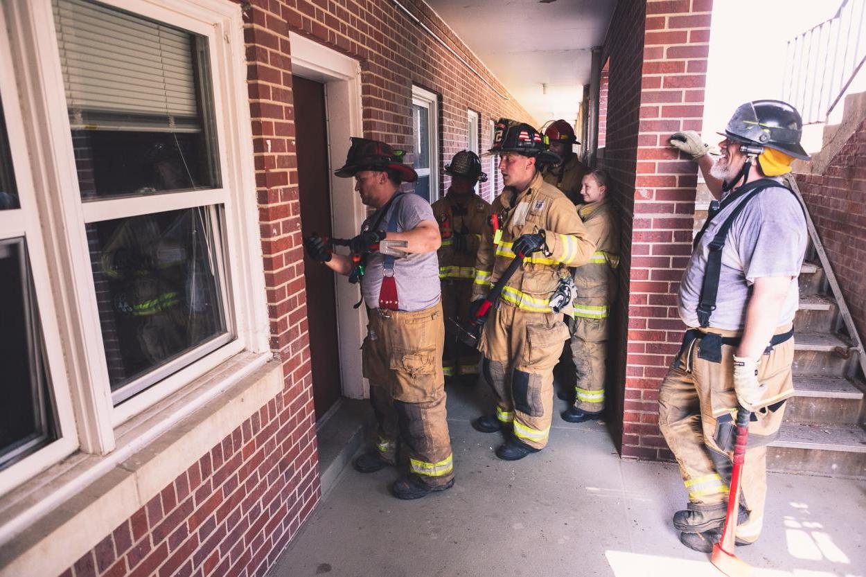 Firefighters watch a demonstration of breaking into a door outside of Burrage大厅. 